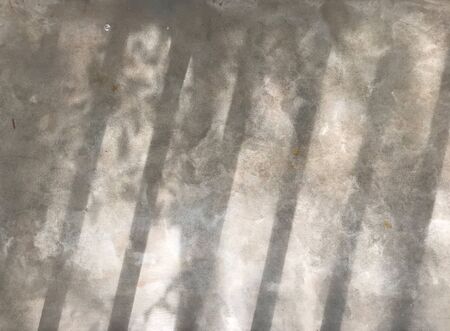 beautiful shadow from baluster bar and small tree leaves shine on gray cement in natural daylight, using for backgroundの写真素材