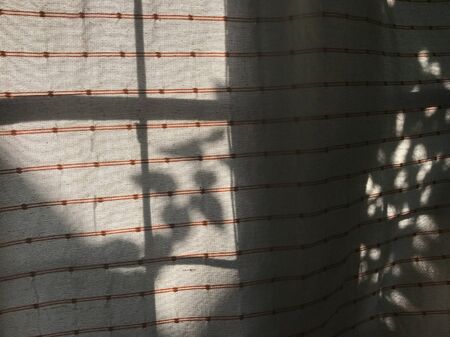 dot and line pattern on natural cotton curtain was waved by wind and shadow of tree leaves reflect on itの写真素材