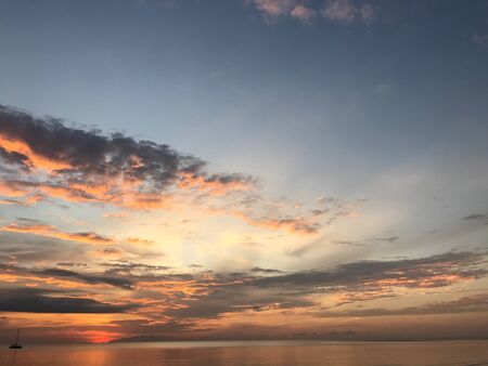 twilight sunset sky and crystal clear ocean surface with one yacht in the seaの写真素材