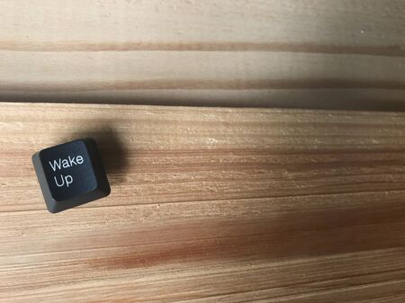 wake up black button from computer keyboard put on natural rubber wood boards in studio with copy space on right side of frameの写真素材