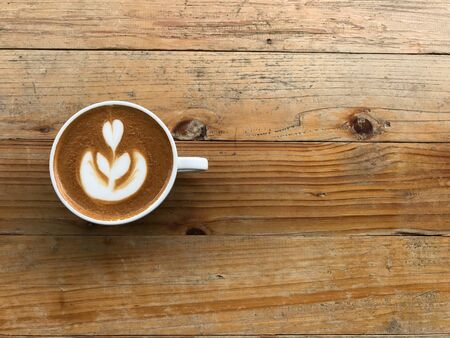 cup of hot cappuccino coffee with beautiful tulip latte art, put on natural brown and retro pattern wood table with copy space at right side of frameの写真素材