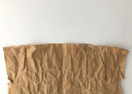 half frame of light brown crumpled paper and white background from top viewの写真素材
