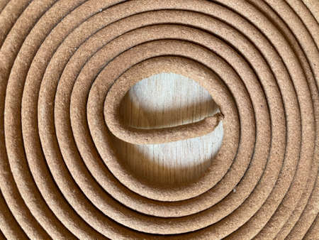 close up shot of twirl traditional natural brown mosquito-repellent on rubber wooden tableの写真素材