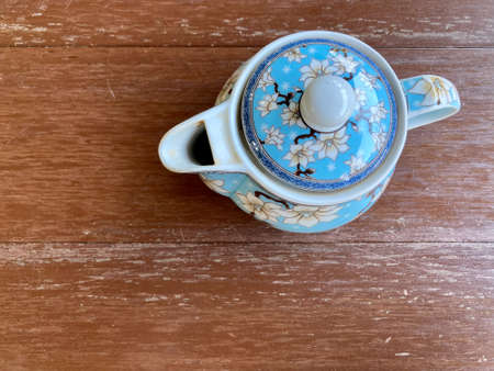 Chinese style teapot with blue flower pattern put on the dark brown table, shot from the top viewの写真素材