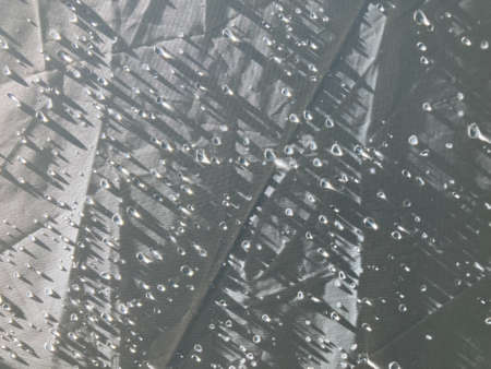 extreme close-up shot of dew drops with sunshine light all over white polyester fabric tent in the early morningの写真素材
