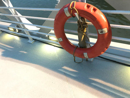 red ring lifebuoy on a white cruise ship with deep-sea in the background in daylight