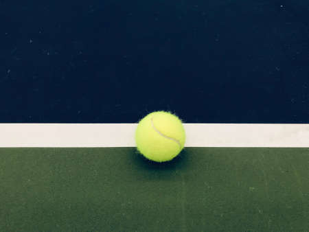 green tennis ball at the middle of the ending white line of tennis blue-green indoor courtの写真素材