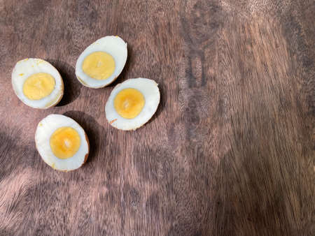 cut in half of two hard-boiled eggs on natural brown wood table in the morning light with copy space...
