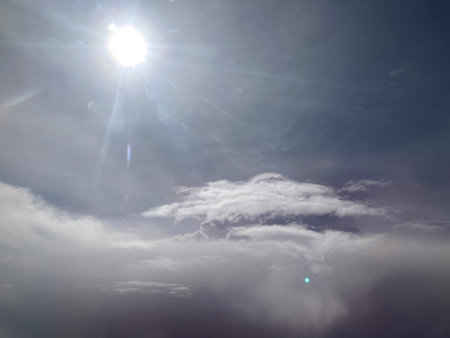 view of the middle of blue sky with white smooth clouds and the big bright sun rays taken from...
