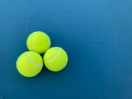 top view shot of three tennis balls on a blue tennis court with the copy space on the right side of frameの写真素材