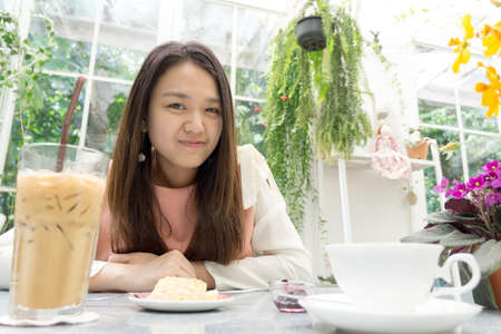 Asian young lady on the dining table with decorative flower and treeの写真素材