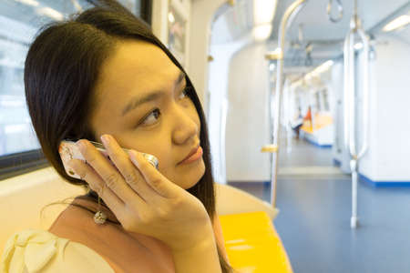 Young lady is calling phone in the sky train