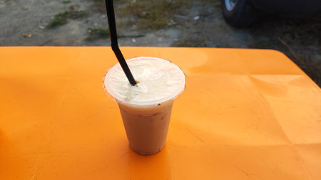 Iced coffee in plastic cup on orange table, top view.の写真素材