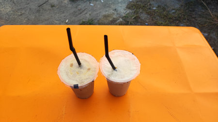Coconut milk smoothies in plastic cup on orange table.の写真素材