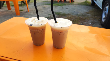 Iced coffee in plastic cup on orange table in coffee shop.の写真素材