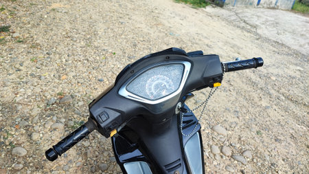 Rear view of a black scooter on a dirt road.の写真素材