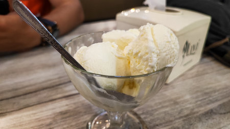 ice cream in a glass bowl with spoon on a wooden table.の写真素材