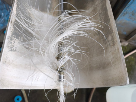 Thin, translucent white plastic strands splay out from a metal industrial component, creating a unique texture. The synthetic fibers suggest a specialized mechanism.の写真素材