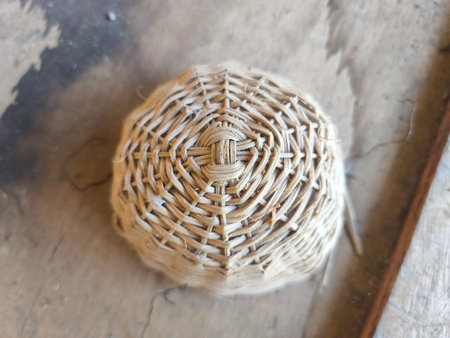 A detailed close-up shot of a round, handwoven basket made from light natural fibers, showcasing its intricate pattern against a blurred background.の写真素材