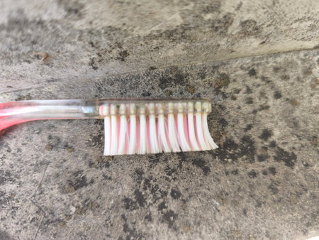 A close-up shot of a toothbrush featuring white and pink bristles, resting on a rough, weathered grey surface, highlighting personal care.の写真素材