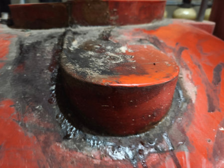 A close-up shot revealing the grimy, reddish-orange surface of an industrial equipment component. The worn metal shows signs of dirt, moisture, and heavy use.の写真素材