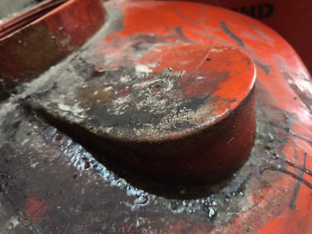 An abstract close-up highlights the rich textures and faded colors of a heavily weathered orange surface, showcasing details of dirt and peeling paint.の写真素材