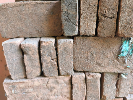 A close-up shot reveals the rough texture and natural patinas of stacked red clay bricks. Ideal for backgrounds or architectural elements.の写真素材