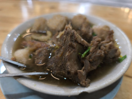 Warm and comforting meat soup, featuring tender ribs, savory meatballs, and fresh green garnish in a...