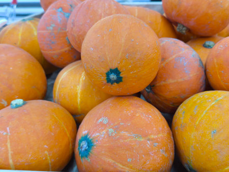 Bright orange pumpkins are piled closely together, showcasing their vibrant color and natural textures for the autumn seasonの写真素材