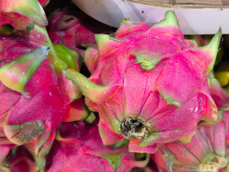 Ripe dragon fruits display vibrant pink skin with prominent green scales, showcasing their exotic beauty The fruits are stacked together, ready for saleの写真素材