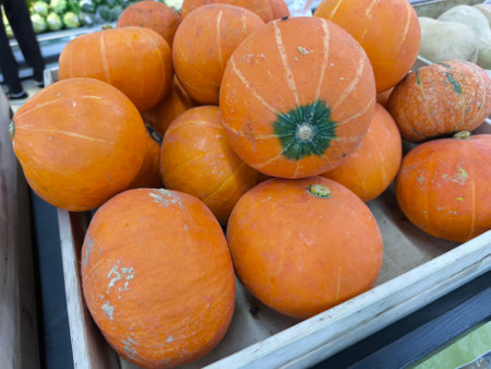 Various vibrant orange pumpkins and squash are neatly arranged in a wooden crate at a market These fresh vegetables are ready for purchaseの写真素材