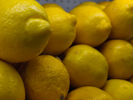 Vibrant yellow lemons are closely stacked, showcasing their distinct textured skins and bright citrus hues in a fresh arrangementの写真素材