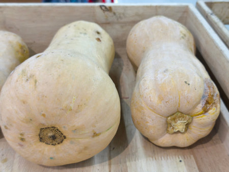 Harvested butternut squash with pale skin rests in a natural wooden container Ready for cooking or display, these vegetables offer a healthy optionの写真素材