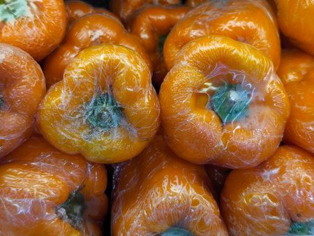 Individually wrapped orange bell peppers show early signs of mold and condensation inside their clear plastic film, indicating spoilageの写真素材