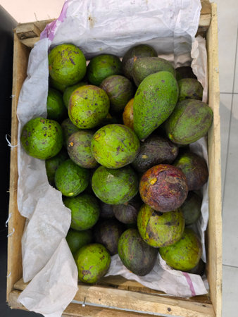 Variety of freshly harvested avocados are neatly arranged inside a rustic wooden crate, cushioned by soft white paper lining, ready for market display or saleの写真素材