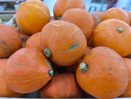 A bountiful display of vibrant orange pumpkins, freshly harvested and piled together, awaits customers in a well lit produce marketの写真素材