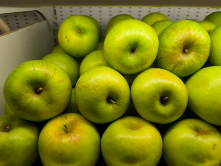 Close up of a vibrant pile of fresh green apples, showcasing their natural textures and slight imperfections in a marketの写真素材