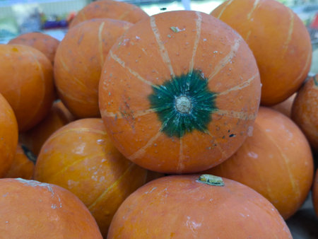 Vibrant orange pumpkins are stacked in a colorful display, highlighting their unique textures and the rich hues of autumnの写真素材