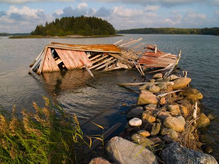 A weathered and fallen down boathouse at the ocean.の写真素材