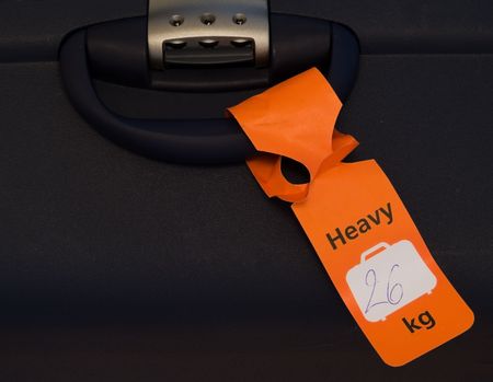 An orange tag on a heavy piece of luggage.の写真素材