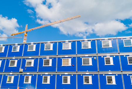 Blue barracks and a crane on a construction siteの写真素材