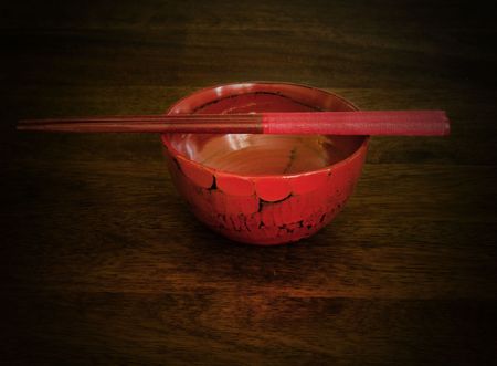 Red chopsticks and a bowl on wooden tableの写真素材