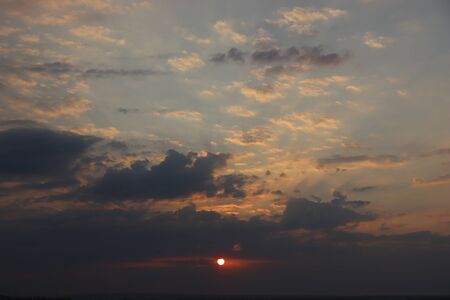 the sun through the gray clouds in the eveningの写真素材