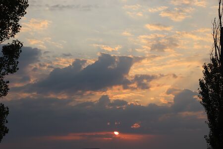 the sun through the gray clouds in the eveningの写真素材