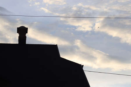 silhouette of a house with a chimney on the background of a cloudy bright skyの写真素材