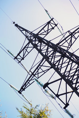 large iron tower of power lines in green area under blue sky