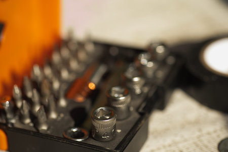 a box with tools, a box with a screwdriver and bits, and electrical tape nearby