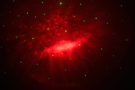 A mesmerizing display of cosmic colors, featuring a vibrant explosion of red hues, surrounded by sparkling star-like dots, resembling a nebula in spaceの写真素材