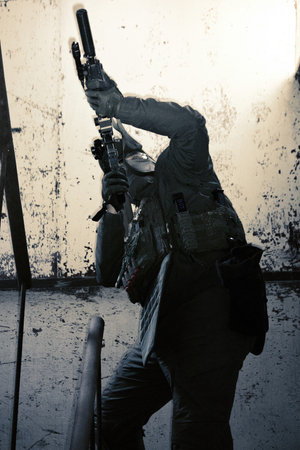 Soldier with assault rifle in abandoned building, silhouette of a soldier