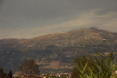 A peaceful village lies at the base of mountains under a soft, overcast sky.の写真素材